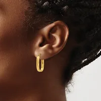 A person wearing a pair of polished gold hoop earrings, shown in profile from the side of their face and neck.
