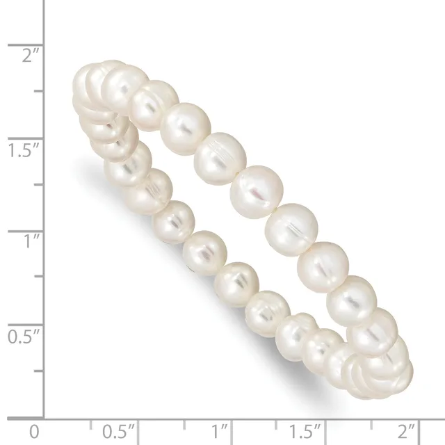 A curved double-strand bracelet of cream-colored pearls with a lustrous finish, displayed against a measurement scale showing approximately two inches in length.