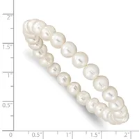 A curved double-strand bracelet of cream-colored pearls with a lustrous finish, displayed against a measurement scale showing approximately two inches in length.