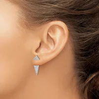 A person wearing two silver triangle-shaped earrings, one pointing upward and one pointing downward, displayed on their earlobe.