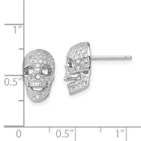 A pair of silver skull-shaped stud earrings with pave crystal embellishments, shown front and side view with a measurement scale.