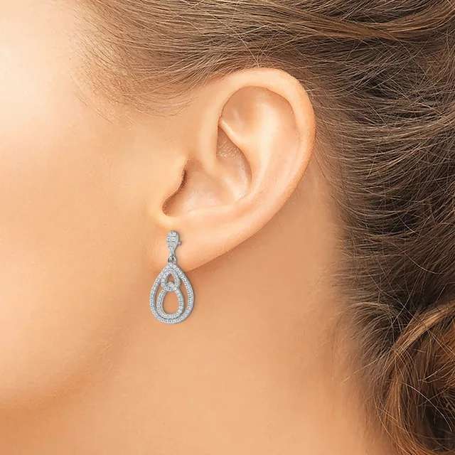 A woman wearing a teardrop-shaped diamond earring with an open center and pave-set stones, shown from the side against her ear.
