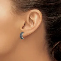 A curved silver earring with dark blue stones set in rows along the surface, worn in a person's earlobe.