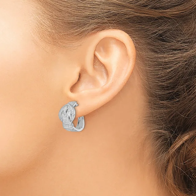 A woman wearing a textured silver hoop earring with a curved, patterned surface, shown from the side profile view against her ear.
