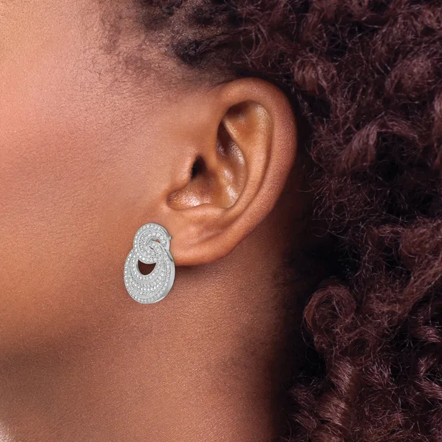 A person wearing a large oval-shaped diamond stud earring with a cutout detail in the center, shown from the side profile.