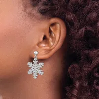 A person wearing a snowflake-shaped drop earring made of rhinestones hanging from a stud post, visible on their earlobe against skin and dark curly hair.