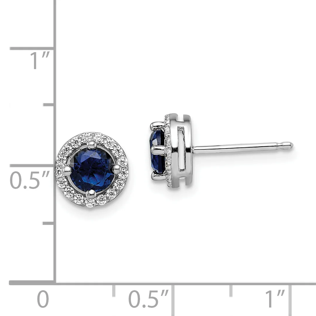 A pair of round stud earrings with deep blue gemstones surrounded by diamond halos, shown front and side view against a measurement scale.