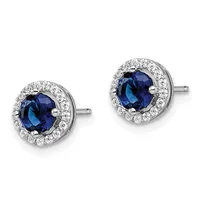 Pair of round stud earrings featuring deep blue sapphires surrounded by halos of small diamonds set in white metal, shown against a white background.