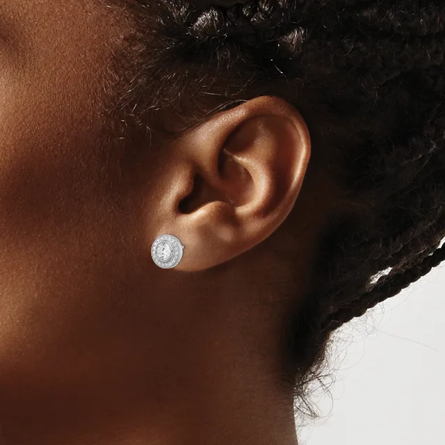 A person wearing a silver stud earring with a round white stone or crystal, shown from the side profile.