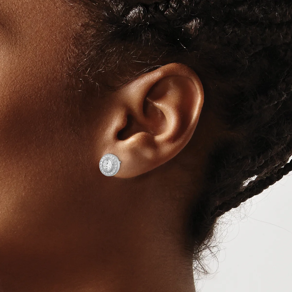 A person wearing a silver stud earring with a round white stone or crystal, shown from the side profile.