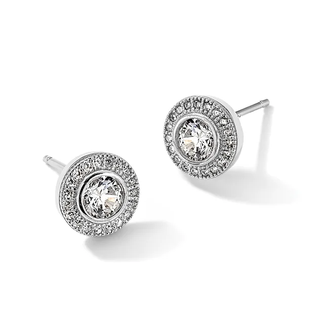 A pair of round diamond stud earrings with a central clear stone surrounded by a halo of smaller diamonds set in white metal, shown from the front.