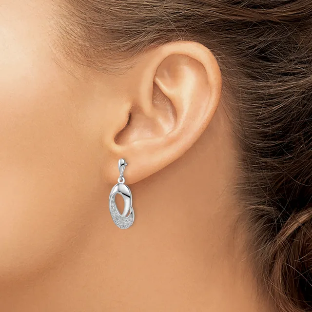 A person wearing a silver drop earring with interlocking oval loops and textured surface detail, shown from the side view of their ear.