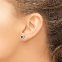 A person wearing a blue sapphire and diamond halo stud earring in their pierced earlobe, shown from the side view.