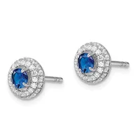Pair of oval stud earrings featuring deep blue sapphires surrounded by halos of round diamonds set in white metal with post backs.