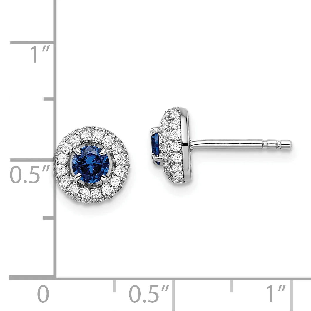 A pair of round stud earrings featuring blue sapphire centers surrounded by diamond halos, shown against a measurement scale indicating approximately 0.5 inches in diameter.
