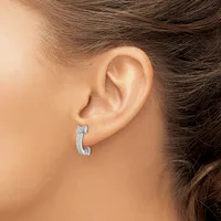 A curved diamond hoop earring in white metal worn in a woman's pierced earlobe, shown from the side view.