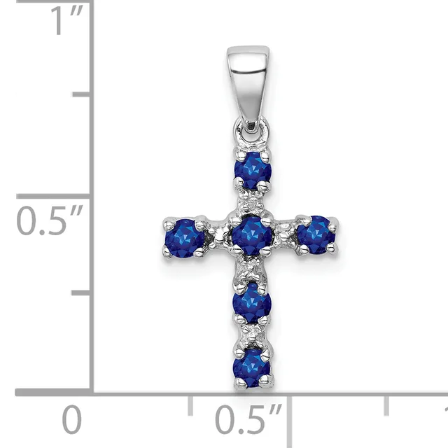 Silver cross pendant with blue gemstones at each point and center, shown against a measurement scale indicating approximately one inch in height.