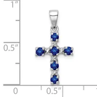 Silver cross pendant with blue gemstones at each point and center, shown against a measurement scale indicating approximately one inch in height.