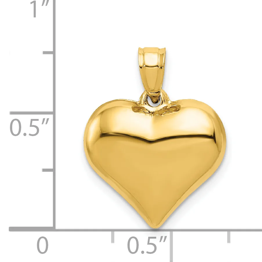 Polished gold-colored heart-shaped pendant with a small bail loop at the top, shown next to a ruler measuring approximately one inch tall and half inch wide.