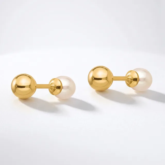 A pair of gold cufflinks with polished gold spheres connected to cream-colored pearl spheres, displayed on a white surface.