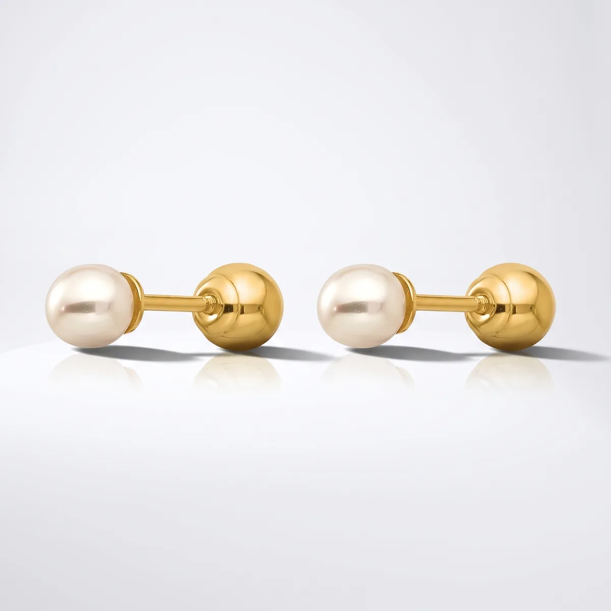 A pair of gold cufflinks, each featuring a cream pearl sphere connected to a polished gold sphere by a short gold bar, displayed on a white surface.