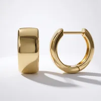 A pair of polished gold-toned chunky hoop earrings with hinged closures displayed on a white surface.