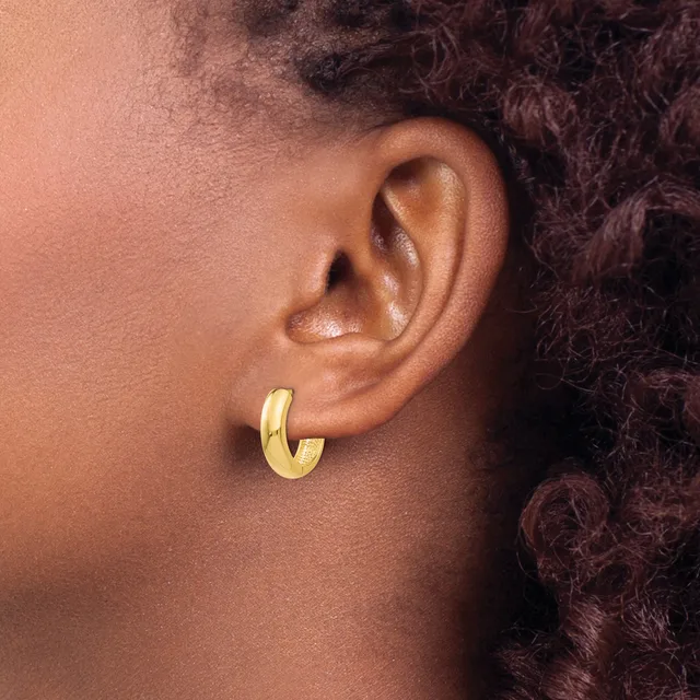 A person wearing a gold-toned chunky hoop earring in their earlobe, shown in profile with textured dark hair visible in the background.