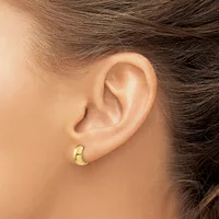 A person wearing a small gold crescent moon-shaped earring is shown in profile, displaying the earring in their earlobe.