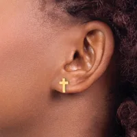 A close-up of a person's ear wearing a small gold cross stud earring.