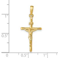 A polished gold crucifix pendant with a figure of Christ depicted on the cross, shown against a ruler indicating approximately one inch in height.