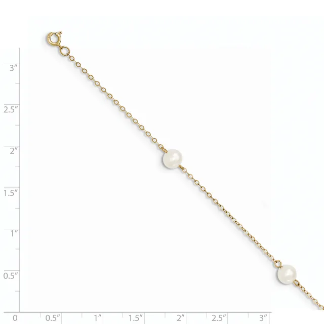 A gold chain bracelet with two pearl stations displayed against a measurement scale.