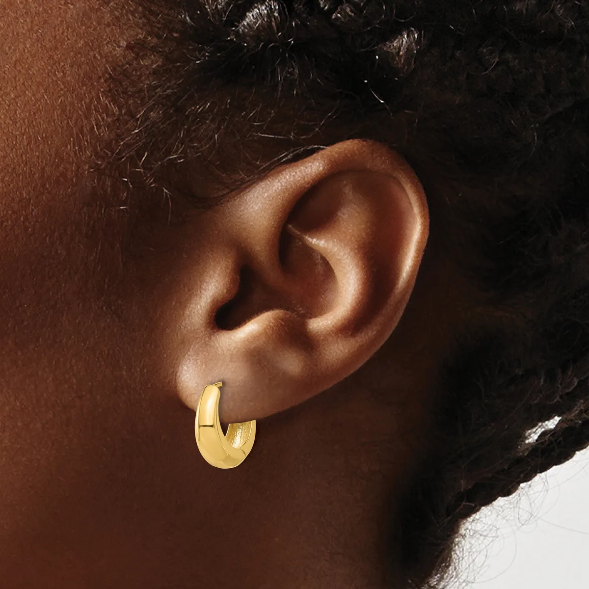 A person wearing a gold hoop earring in their earlobe, shown in profile against their brown skin tone.