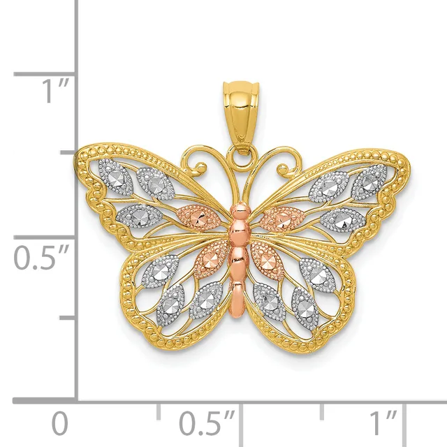 A gold butterfly pendant with filigree wings decorated with cubic zirconia stones and a rose gold body, shown against a measurement scale.