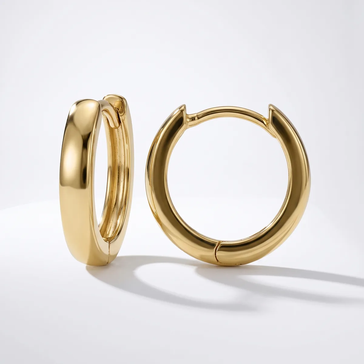 A pair of polished gold hoop earrings with a chunky, rounded profile displayed against a white background.
