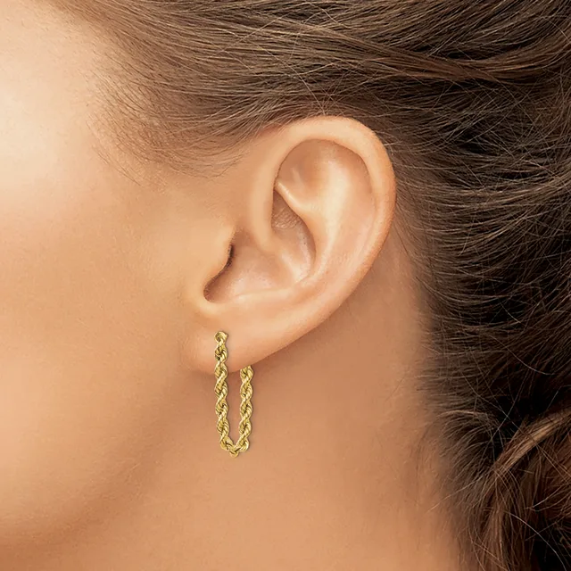 A person wearing gold textured hoop earrings with a twisted or braided pattern, shown from the side profile of their ear and neck.