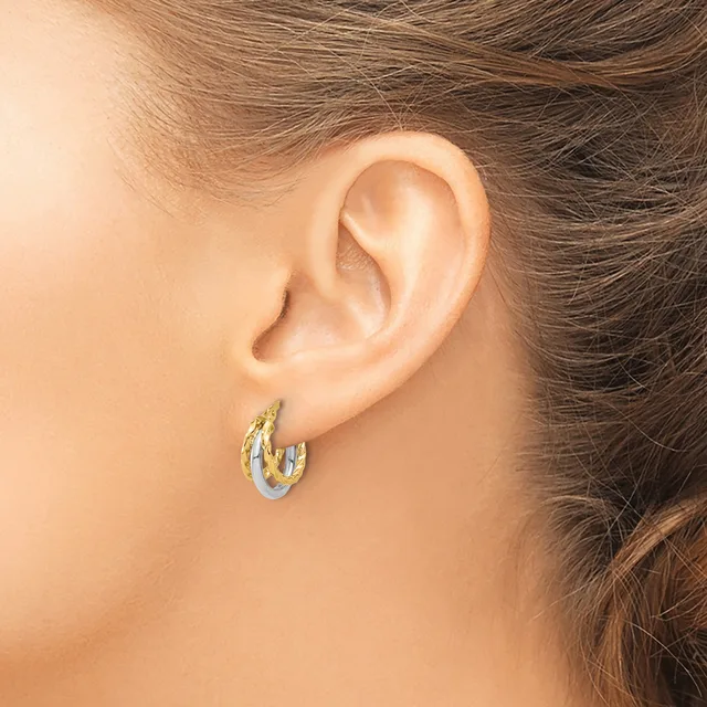 A close-up side view of a person's ear wearing a small two-tone hoop earring with gold and silver coloring.