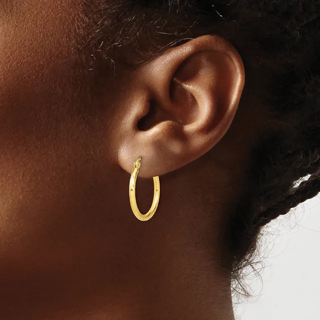A person wearing a gold hoop earring on their earlobe, shown in profile against a neutral background.