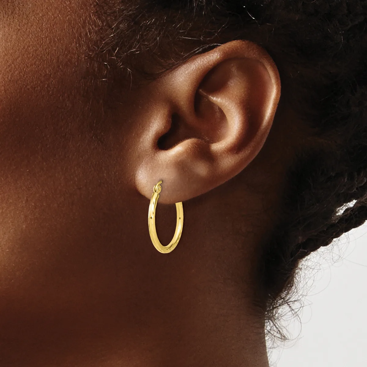A person wearing a gold hoop earring on their earlobe, shown in profile against a neutral background.