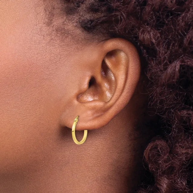 A person wearing a small gold hoop earring in their earlobe, shown in profile view against their skin.