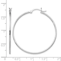 A pair of polished silver hoop earrings displayed next to a ruler showing their size as approximately 1.5 inches in diameter.