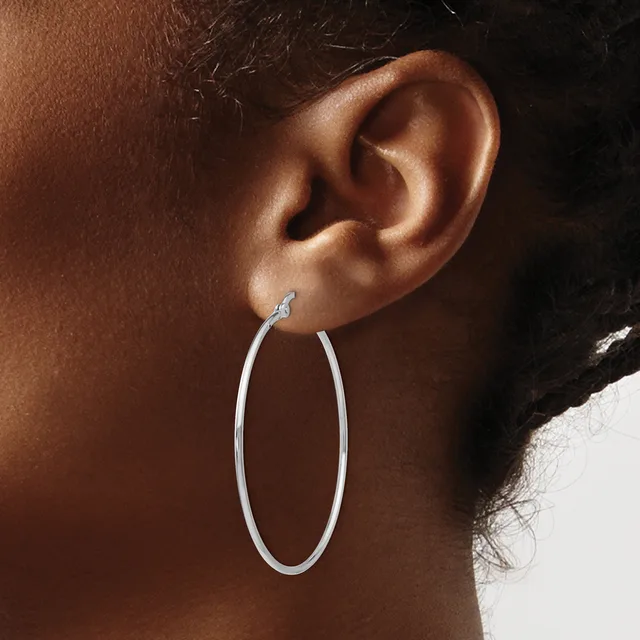 A woman wearing a large silver oval hoop earring, shown from the side with her ear and part of her neck visible against a neutral background.