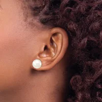A person with deep brown skin and dark curly hair wears a white pearl stud earring in their earlobe, shown in profile from the side.