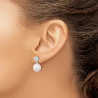 A woman wearing a pearl drop earring with a diamond-set silver post is shown in profile from the shoulder up.