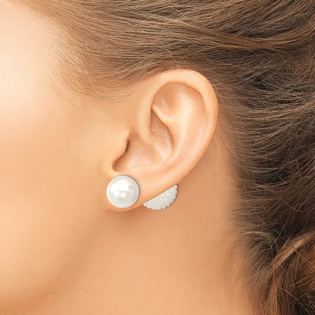 A person wearing mismatched pearl stud earrings—one round white pearl and one small white textured wing-shaped stud—shown from the side profile view.