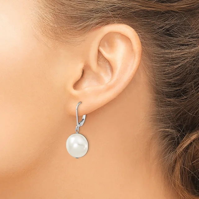 A woman wearing a silver lever-back earring with a white pearl pendant hanging from it, shown from the side profile of her ear and neck.