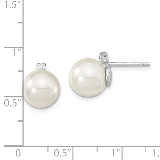Two pearl stud earrings with diamond accents displayed next to a ruler showing they measure approximately one inch in diameter.