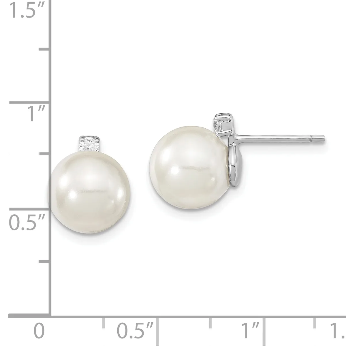 Two pearl stud earrings with diamond accents displayed next to a ruler showing they measure approximately one inch in diameter.