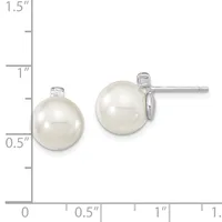 Two pearl stud earrings with diamond accents displayed next to a ruler showing they measure approximately one inch in diameter.