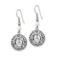 A pair of silver dangle earrings with ornate circular filigree pendants each containing a white pearl, suspended from pearl beads on fish hook wires.
