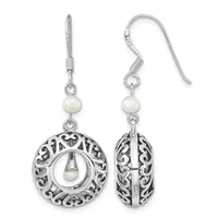 A pair of silver filigree circular earrings with pearl accents, shown from front and side views, hanging from curved ear wires.